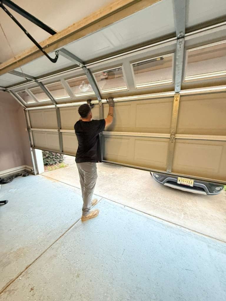 Technician checking a sectional garage door with windows from inside the garage