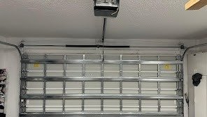 Ceiling-mounted garage door opener above a closed steel door with reinforcing struts