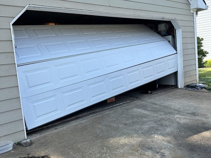 White garage door jammed crooked in its opening