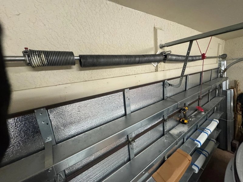 Torsion spring on the steel shaft above an insulated sectional door with struts